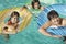 Siblings With Inflatable Rafts Enjoying Together In Swimming Pool