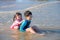 Siblings laughing happily after being hit by the sea