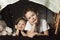 Siblings lie in a hut of chairs and blankets. Brother and sister smiling playing at home