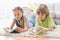 Siblings reading books while lying on rug