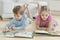 Siblings reading story books on floor in the living room