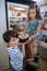 Siblings removing cake from refrigerator in kitchen