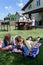 Siblings resting on american flag with family having picnic behind