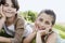 Siblings Resting Chin In Hands While Lying On Grass