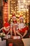 Siblings sisters in santa hats near fireplace on Christmas ligh