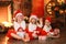 Siblings sisters in santa hats near fireplace on Christmas ligh