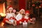 Siblings sisters in santa hats near fireplace on Christmas ligh