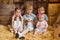Siblings sit on hay in a rustic barn surrounded by wooden boxes and a barrel
