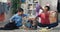 Siblings sit on the laundry room floor sorting colored clothes before putting them in the washing machine, doing