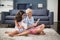 Siblings sitting on rug and using digital tablet in living room