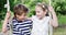 Siblings sitting on a swing in the park