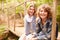 Siblings sitting on a wooden bridge in a forest, portrait