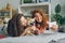 Siblings taking selfie with cute puppy lying on couch at home using smartphone