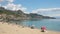 Sicilian beach in Giardini Naxos and ancient Taormina town on a hill in Sicily