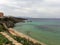 Sicilian sandy beach with bathers in the sea and promontory in the background