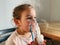 Sick adorable preschool girl with nebuliser mask at home. Treatment for bronchitis with inhaling medicine nebula.