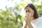 Sick adult woman blowing nose with tissue in the park