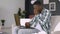 Sick African man in casual clothes, with thermometer in hands, having video call with doctor on laptop