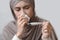 Sick arabic woman in headscarf holding thermometer and blowing runny nose