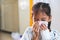 Sick asian child girl who have IV solution bandaged wiping and cleaning nose with tissue on her hand in hospital