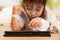 Sick asian little child girl who have IV solution bandaged playing digital tablet to relax