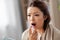 Sick asian woman using oral spray medicine at home