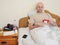 Sick bald unshaven man in his bad with medicine pills in his hands in his bed, concept flue and corona virus treatment