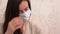 Sick beautiful Caucasian Russian brunette woman in beige jersey in blue protective medical face mask cover her mouth