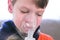 Sick boy inhaling through inhaler mask, face close-up view. Use nebulizer and inhaler for the treatment.