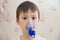 Sick boy in nebulizer mask making inhalation, respiratory procedure by pneumonia or cough for child