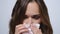 Sick businesswoman sneezing in napkin.Girl with flue looking at camera in studio