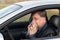 A sick driver wipes his nose with a handkerchief at the wheel