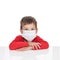 The sick five-year-old boy sits at a white table with medicine healthcare mask