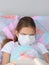 The sick girl decided to fall asleep while reading a book and pulled a medical mask over her face