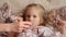 Sick little girl lying in her bed and mother checking temperature of her sick daughter in her mouth