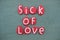 Sick of love, creative message composed with red colored stone letters over green sand