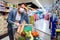 Sick man with fever leaning on shopping cart in supermarket