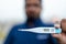 Sick man holds digital thermometer with body temperature reading in Fahrenheit up close to the camera