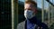 Sick man with surgical mask on face is standing alone on street during pandemic of coronavirus