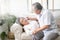 Sick old woman with thermometer laying in sofa and husband hand