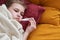 Sick preteen girl laying in bed using thermometer