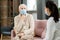 Sick senior man in casualwear and mask complaining doctor about sore throat