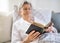 Sick senior woman reading bible book in bed at home or in hospital.