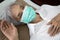 Sick senior woman wear a mask lying in uncomfortable bed,unwell,exhausted old people have a fever,cold and flu,tired elderly