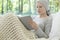 Sick woman with cancer reading a book on a sofa in the hospice