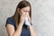 Sick woman with handkerchief sitting at home with flue, virus, cold, seasonal allergy symptom. Young woman blows her nose or