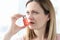 Sick woman holding hormone inhaler near mouth