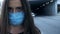 Sick young female putting safety mask on, big city pollution, epidemic virus