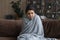 Sick young Indian woman wrapped in blanket feeling unhealthy