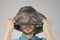 Sickly man with cracked lips removes or puts black plastic bag from his head, gray background, concept big ecology problem
